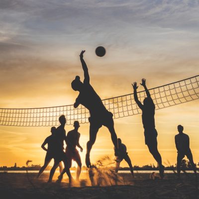Two beach volleyballs on sand at sunset