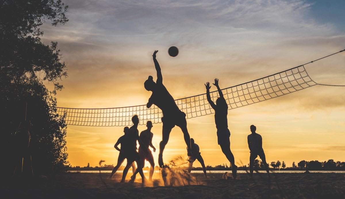 Two beach volleyballs on sand at sunset