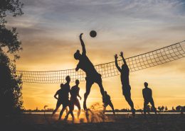 Two beach volleyballs on sand at sunset